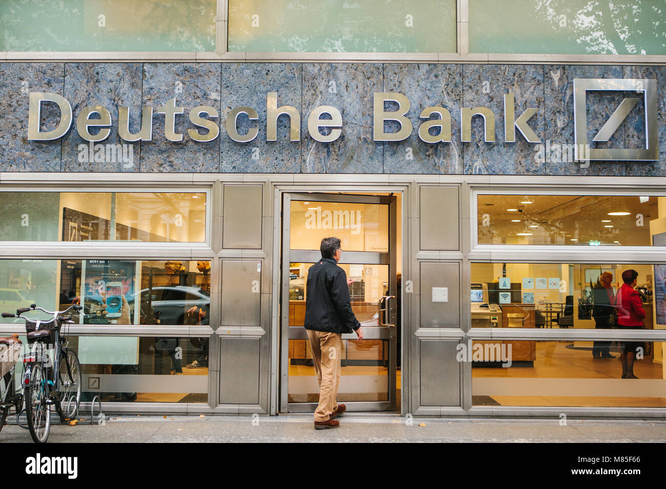 Unknown man walks into the beautiful glass office of Deutsche Bank Stock Photo