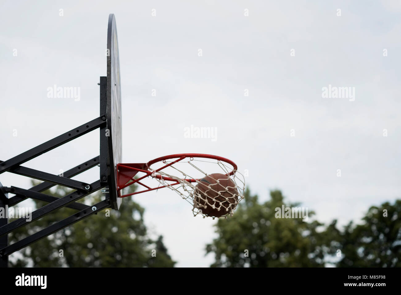 Street basketball game. Basketball shield, ball going through basket on  background of sky, trees. Concept of sport, hit accuracy, active lifestyle  Stock Photo - Alamy