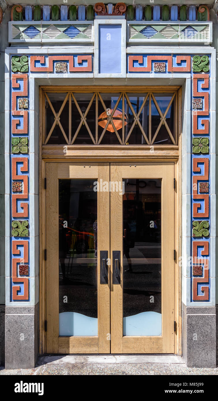 exterior wooden front door with glass and multi-colored stucco ornament, on a city street on a summer day Stock Photo