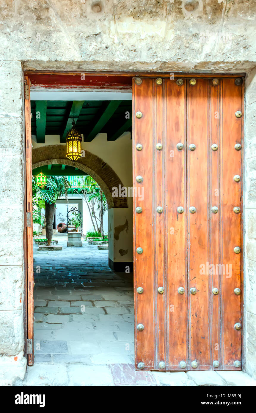 ancient wooden gate in a gray stone wall, in a courtyard with an arch ...