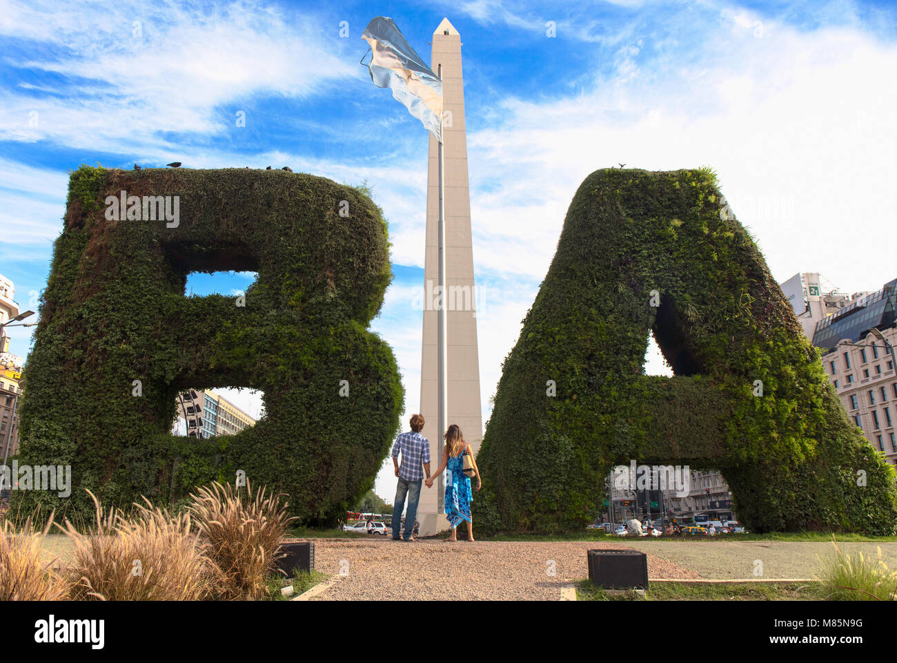 A couple of tourist hand in hand in front of the Obelisk monument on Avenida 9 de Julio. Buenos Aires, Argentina. Stock Photo