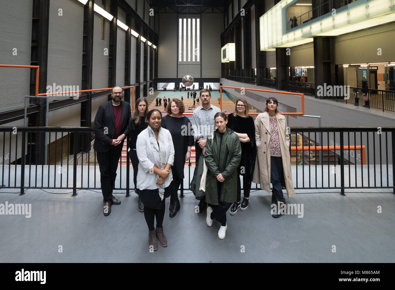 London, UK. 15th March, 2018. Artists (left to right), Ari Benjamin Meyers, Holly Hendry, Mae-ling Lokko, Sally Tallant (Director, Liverpool Biennial), Paul Ellman, Janice Kerbal, Kitty Scott (co-curator, Liverpool Biennial and Rehang Zaman posing for photos in the Turbine Hall of the Tate Modern in London for the launch of the programme for the 10th Liverpool Biennial, opening on 14 July 2018 in venues across Liverpool, marking its 20th anniversary. Credit: Roger Garfield/Alamy Live News Stock Photo