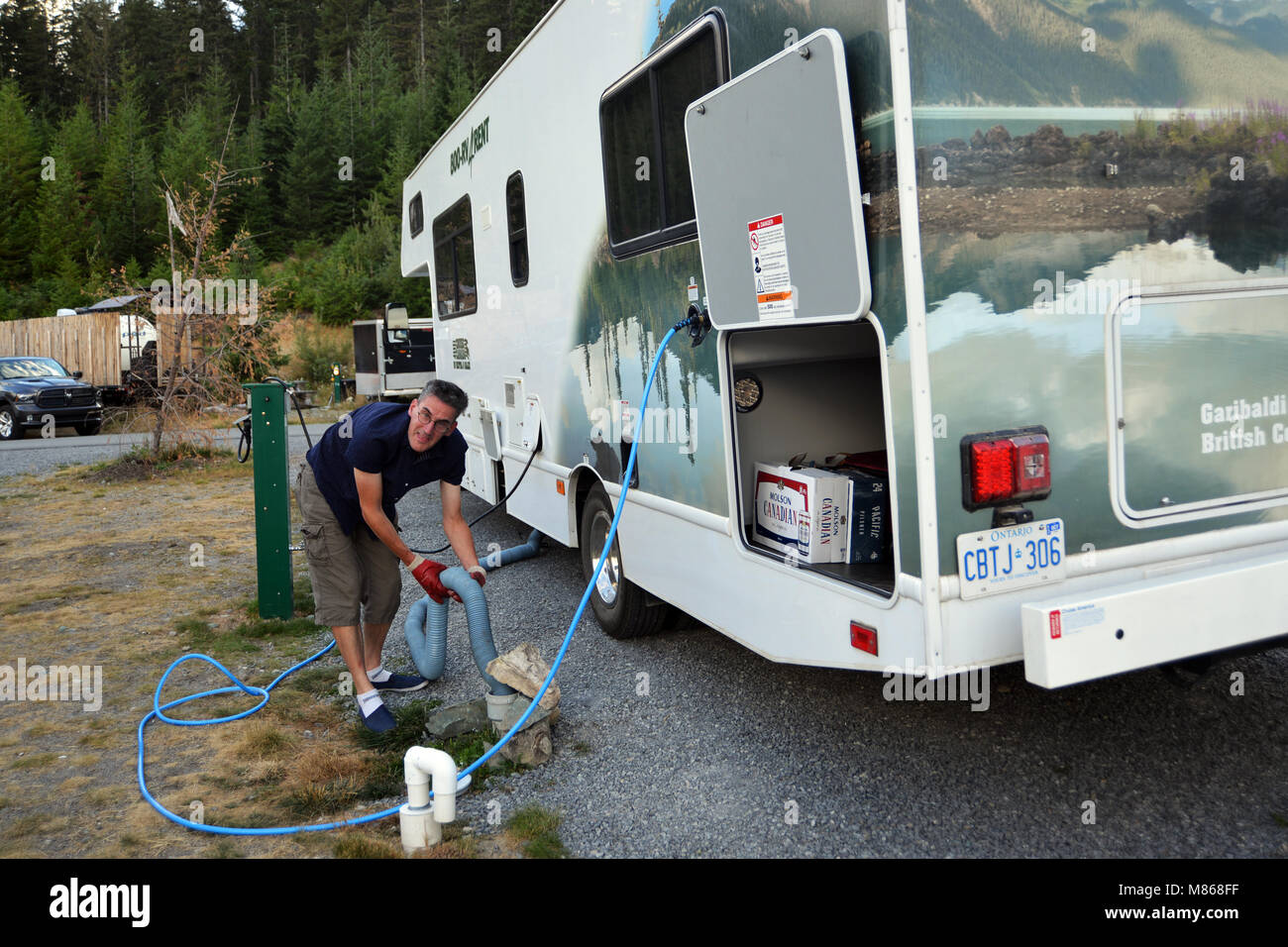 RV vacation Canadian Rockies, Canada man empties dump tank on  holiday model released Stock Photo