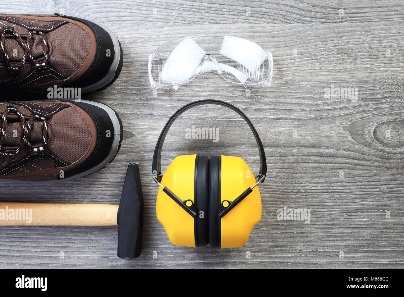 Working tools and wear on wood background. Protective glasses and headphone from above. New working shoes close-up. Workwear theme with free space for Stock Photo