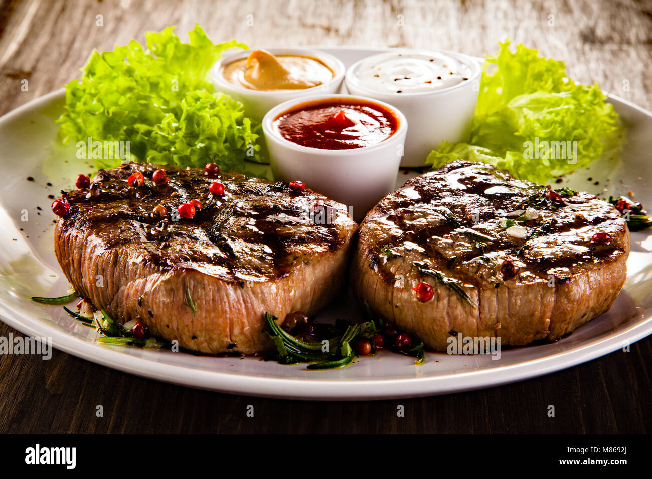 Grilled beefsteaks and vegetables  on wooden table Stock Photo
