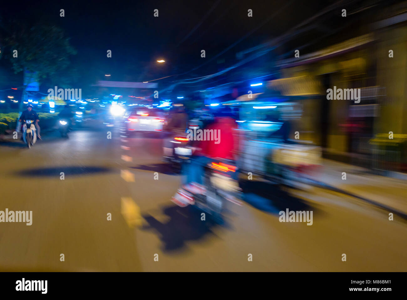 Traffic moving at speed along a street at night in Hoi An, Vietnam Stock Photo
