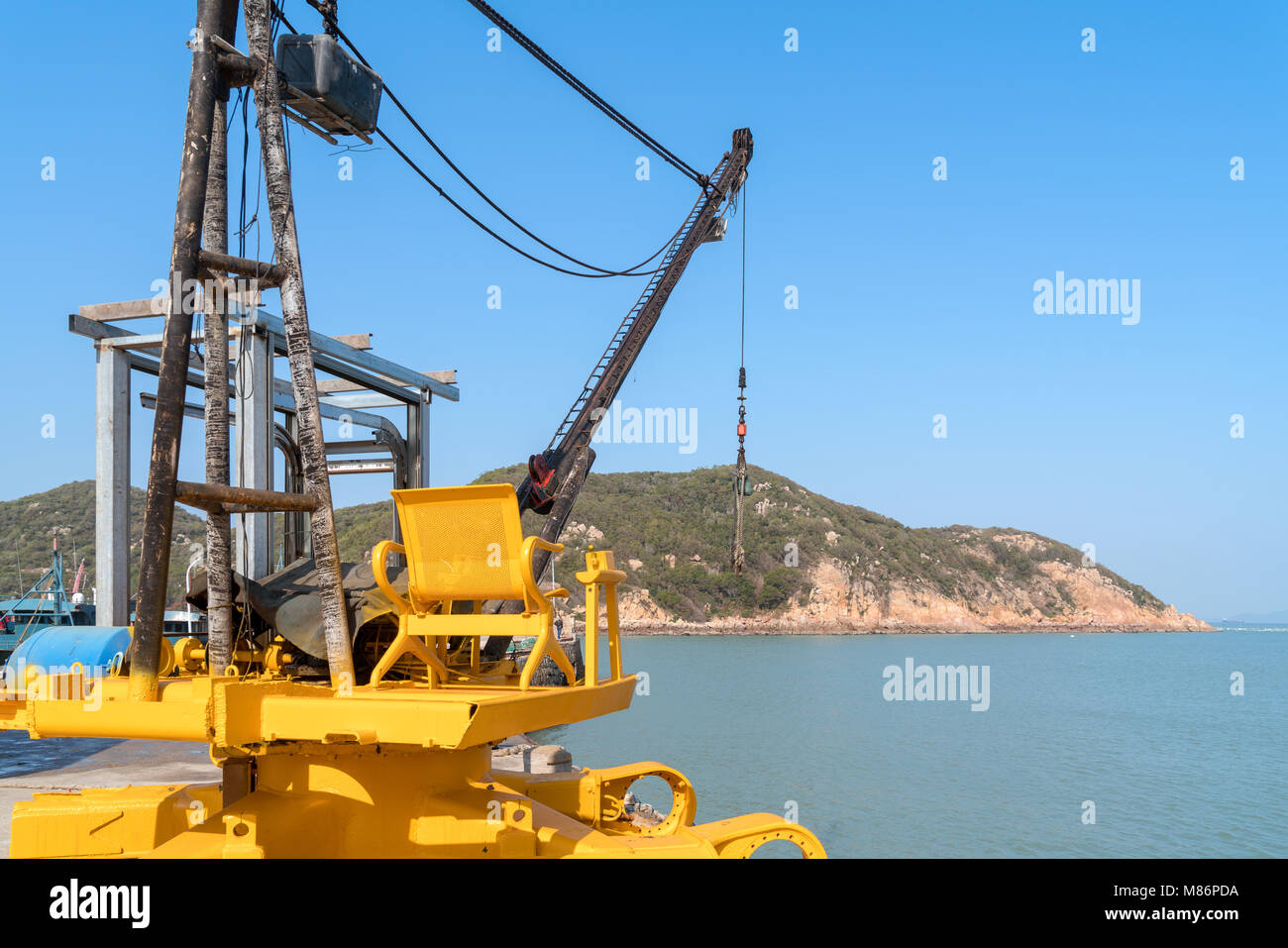 Fishing boat dock, crane against blue sky background Stock Photo - Alamy