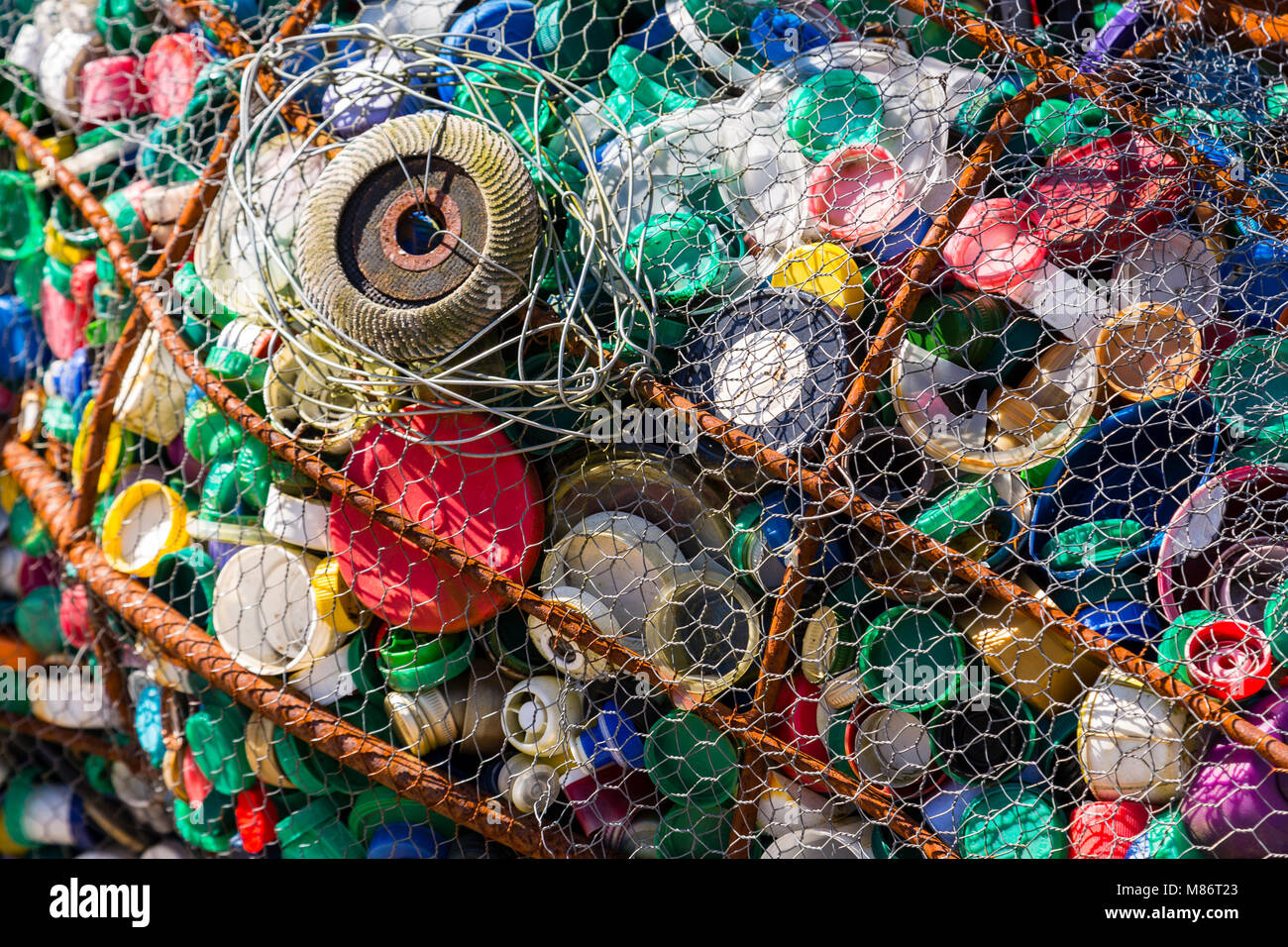 Waste plastic bottle tops in a wire mesh frame Stock Photo