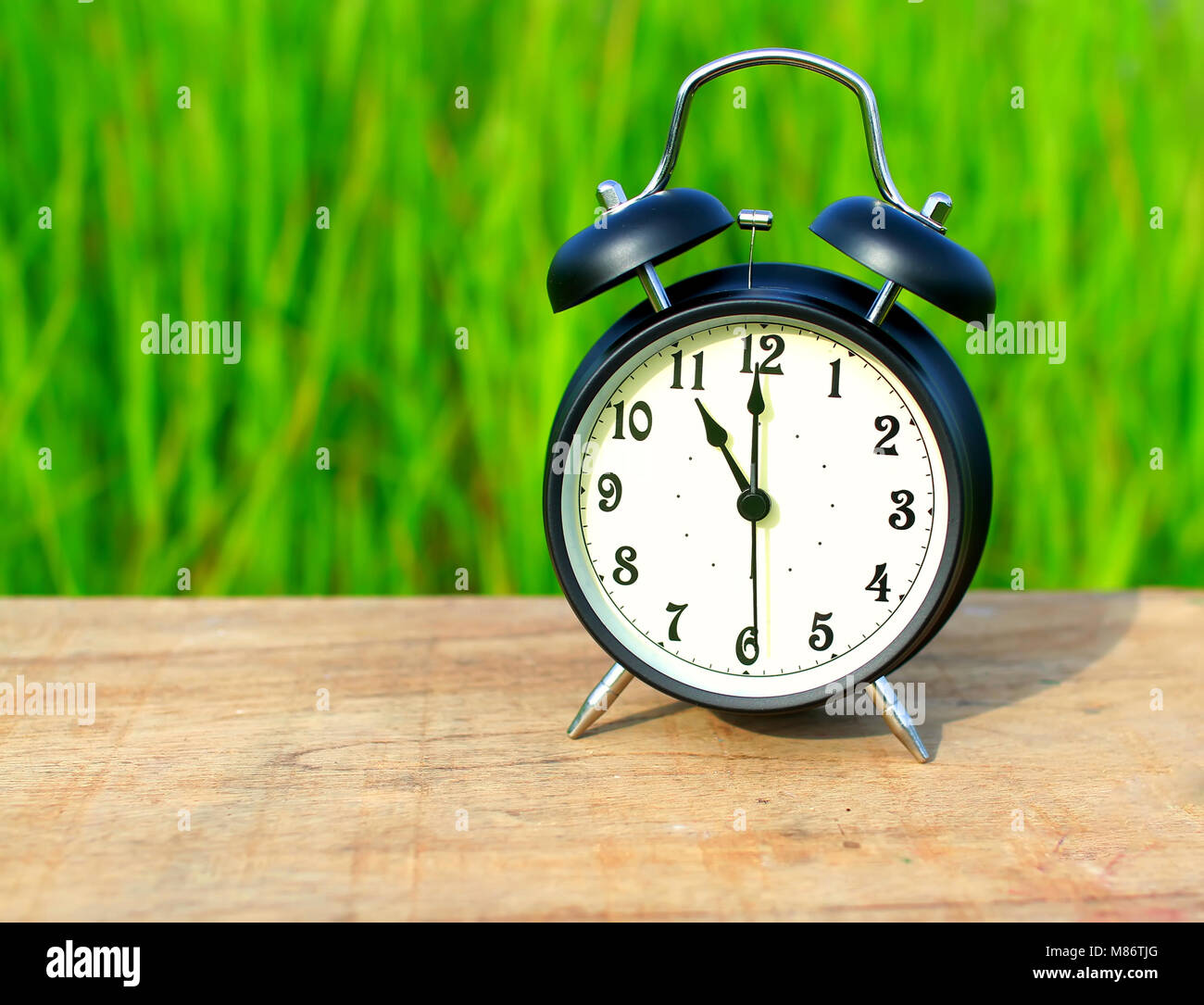 Alarm clock on table with grass background Stock Photo