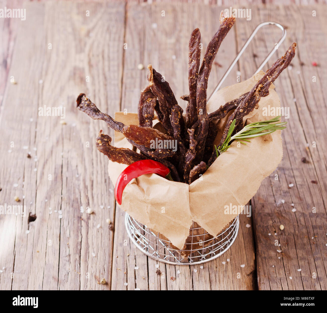 jerked dried meat, cow, deer, wild beast or biltong in wooden bowls on a rustic table, selective focus Stock Photo