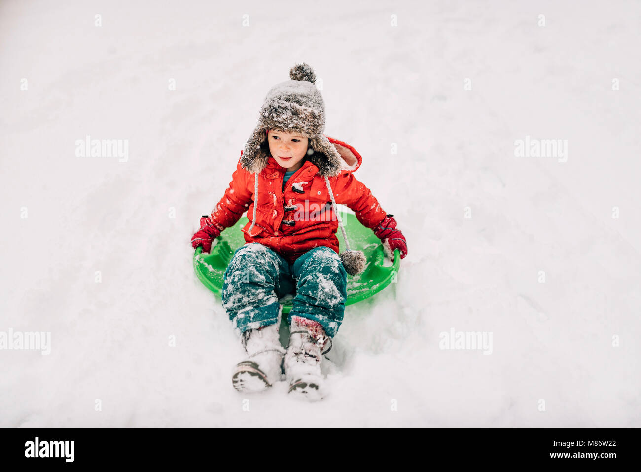 Young girl sledging in the heavy snow Stock Photo