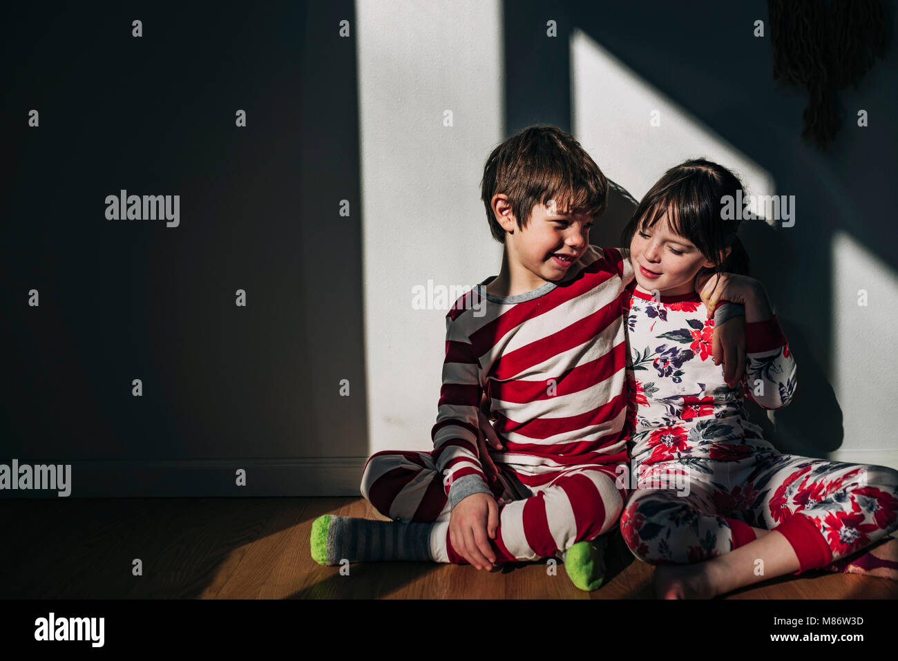 Boy and girl sitting on floor hugging Stock Photo - Alamy