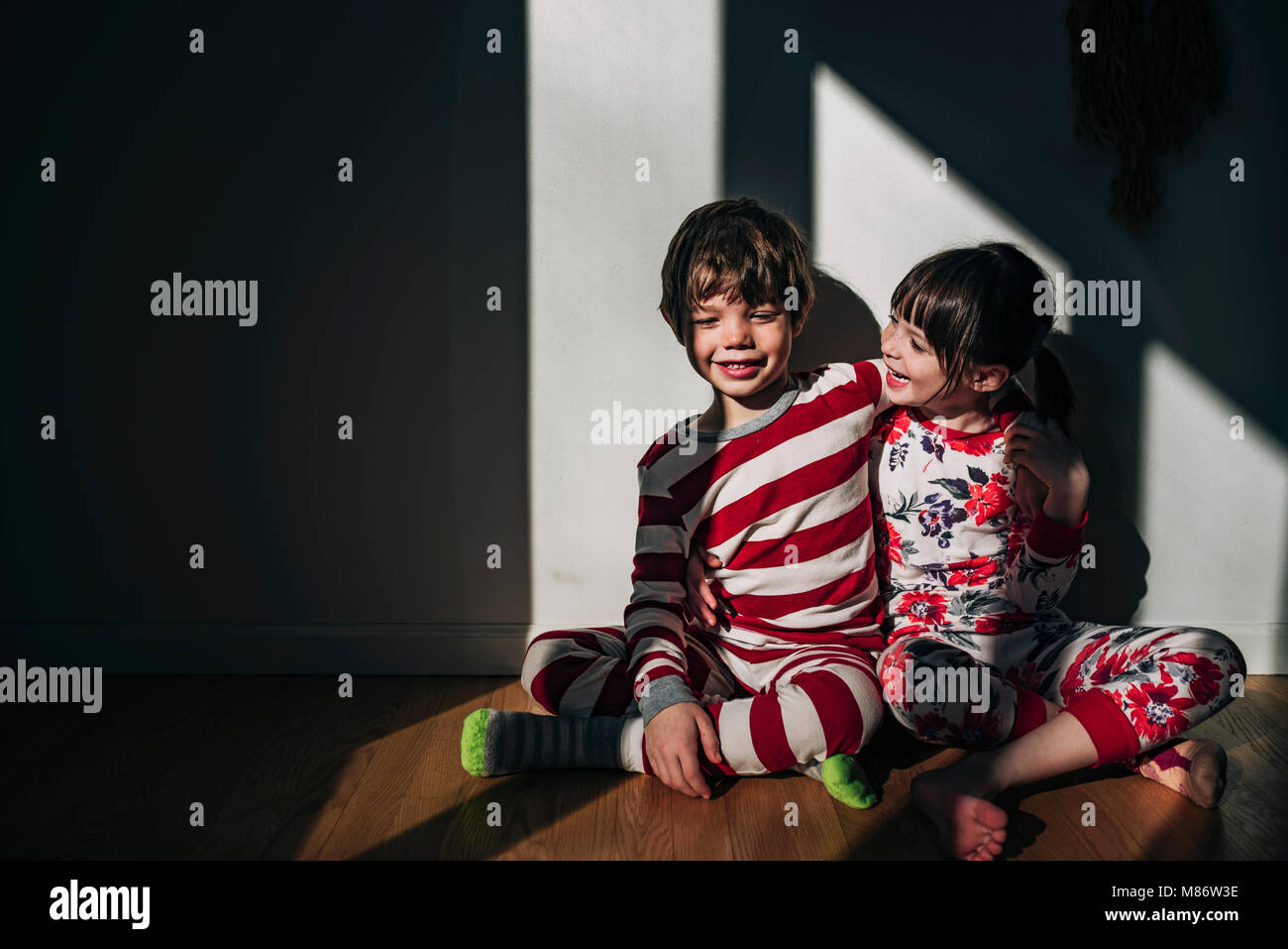 Boy and girl sitting on floor hugging Stock Photo - Alamy