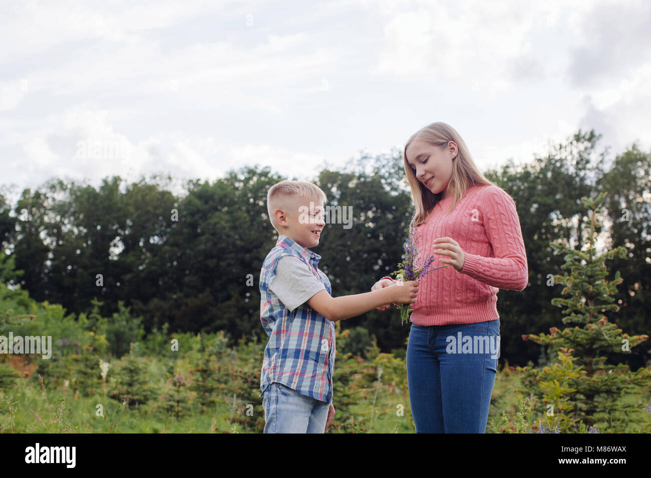 Boy giving a girl freshly picked flowers in a meadow Stock Photo