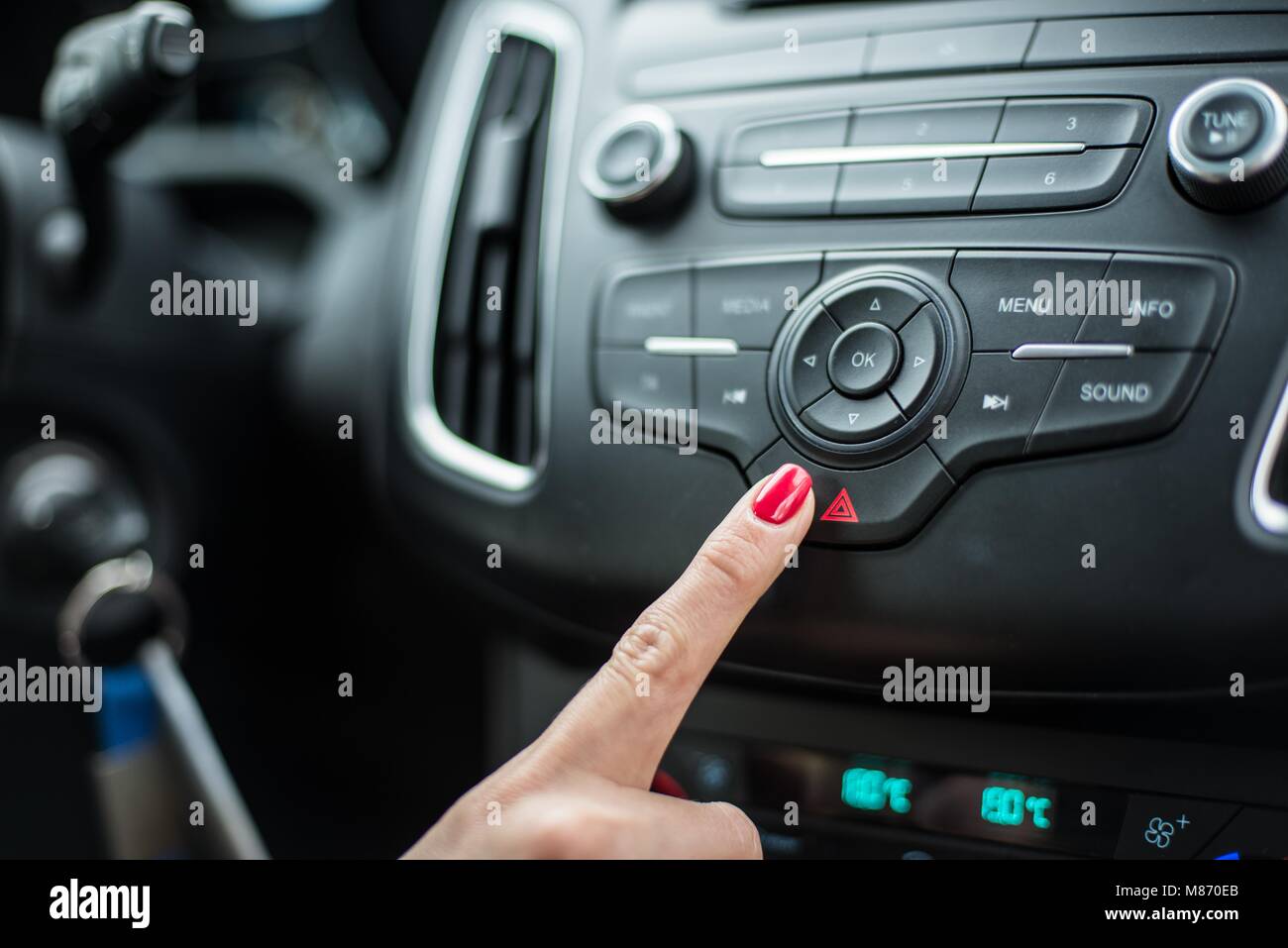 Woman pushing car emergency lights button. Modern car interior Stock