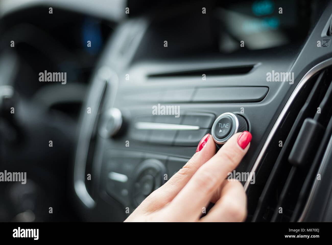Woman changing frequency on car radio. Modern car interior Stock Photo
