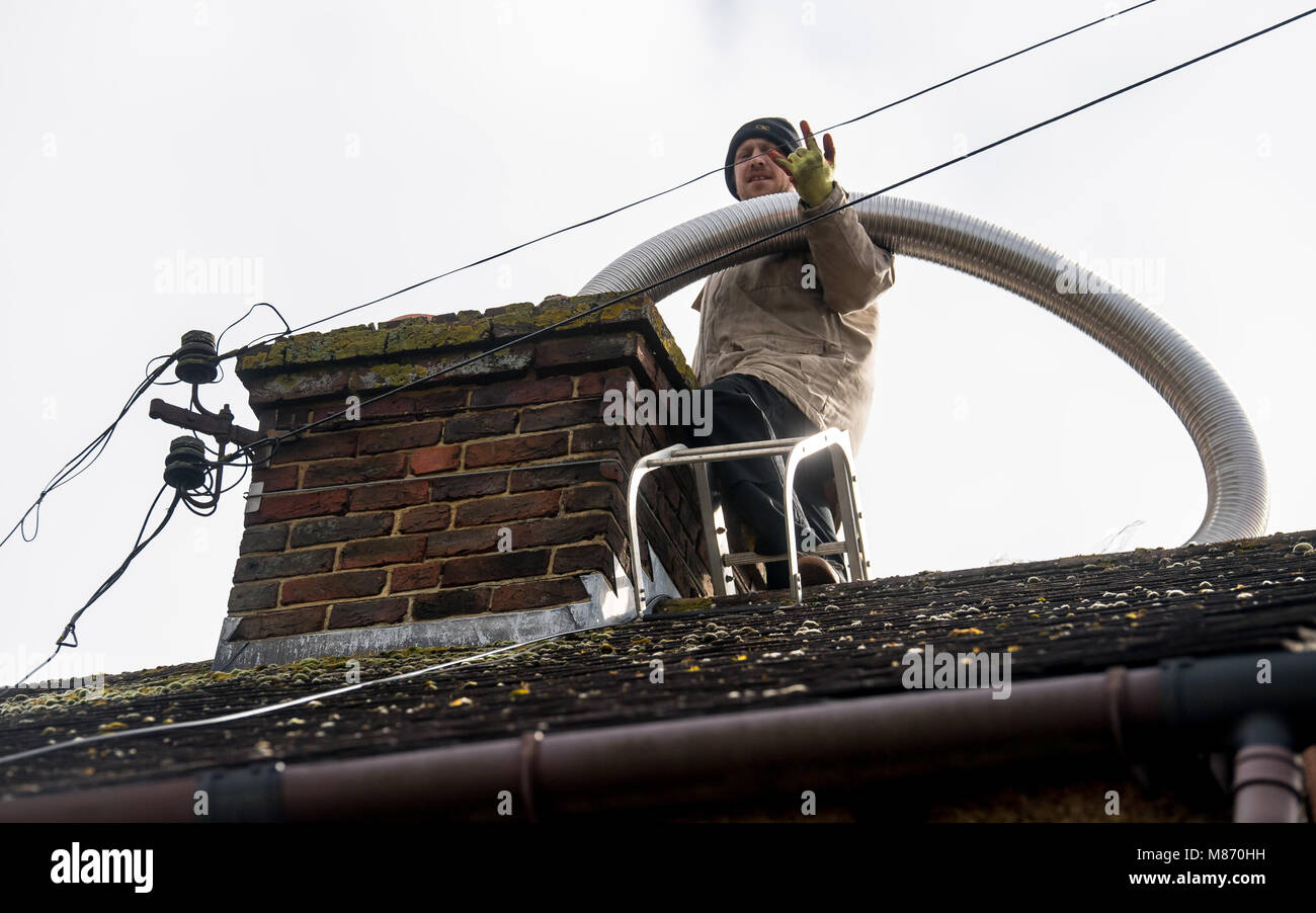 An engineer installs flue pipe down a chimney to ensure safety of a log