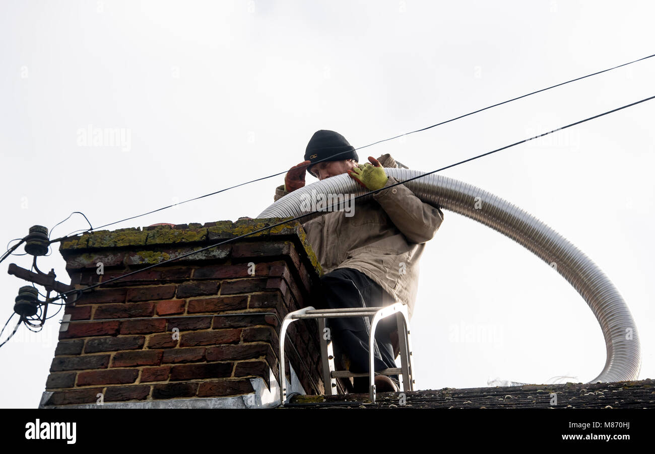 An engineer installs flue pipe down a chimney to ensure safety of a log burner's operation. Stock Photo