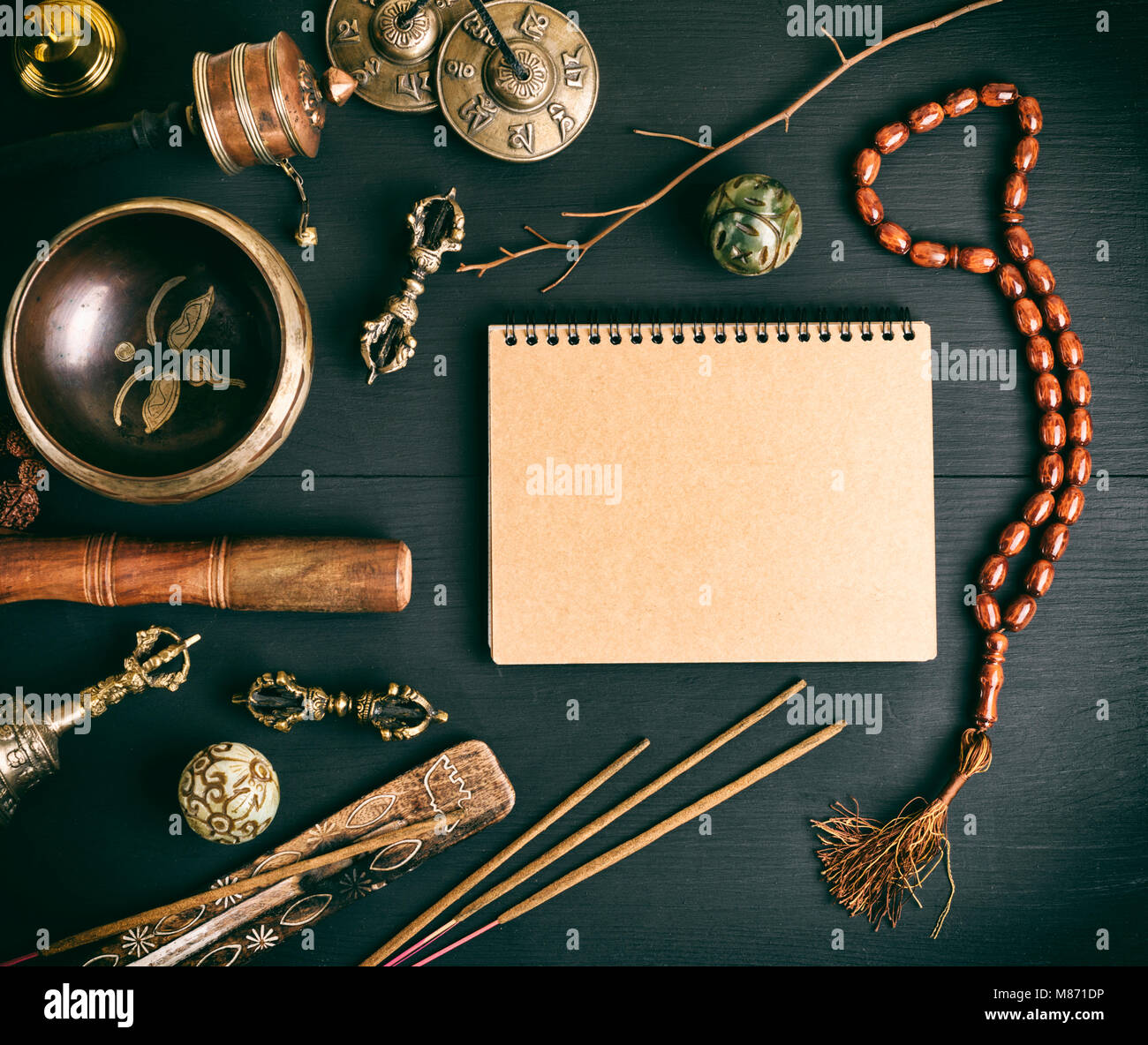 Asian religious musical instruments for meditation and alternative medicine, blank notebook with brown sheets on a black wooden background, top view Stock Photo