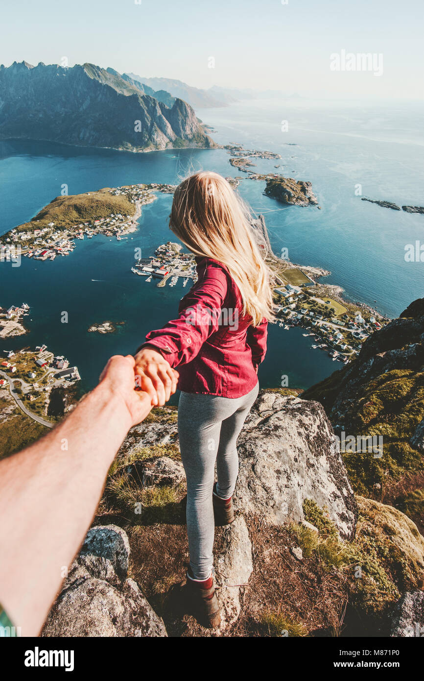 Couple follow holding hands traveling lifestyle on cliff mountain summer vacations outdoor in Norway Stock Photo