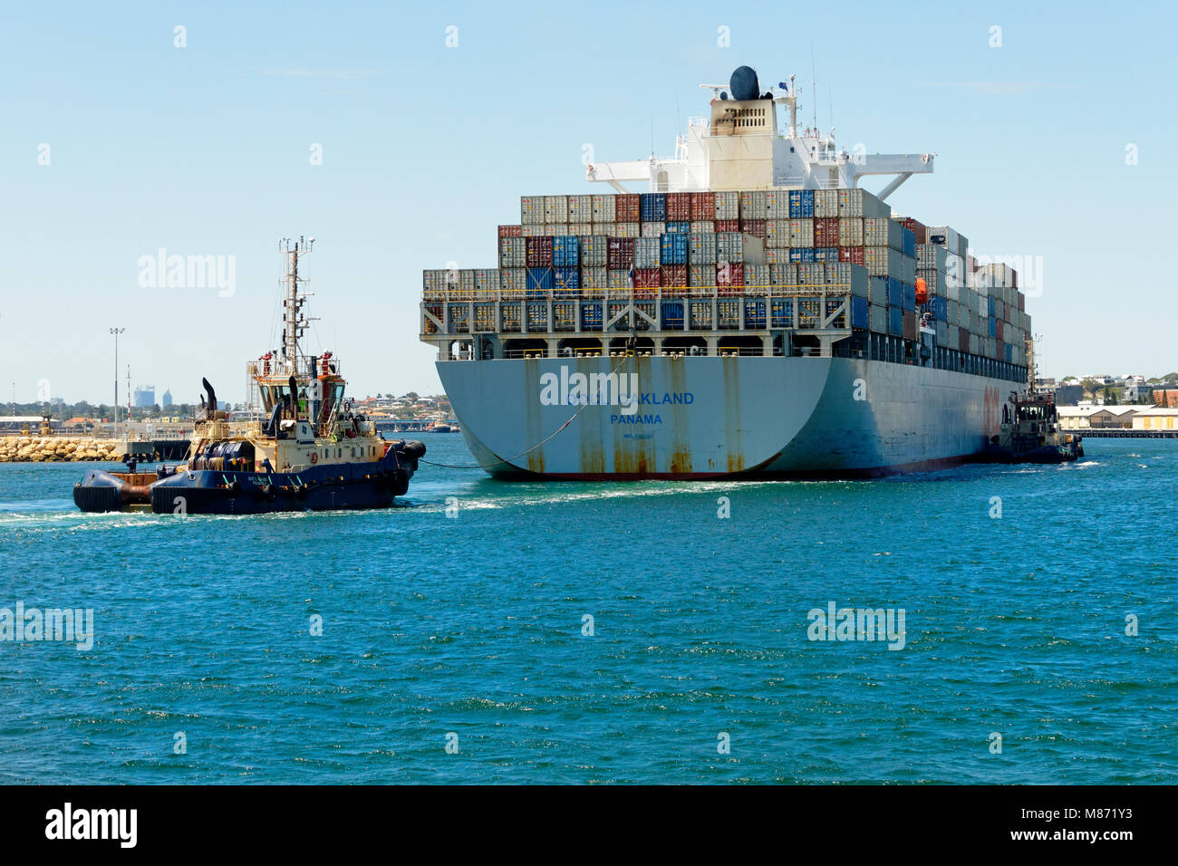 Container ship OOCL OAKLAND (Panama) with tug boats alongside  entering Fremantla harbour, Fremantle, Western Australia Stock Photo