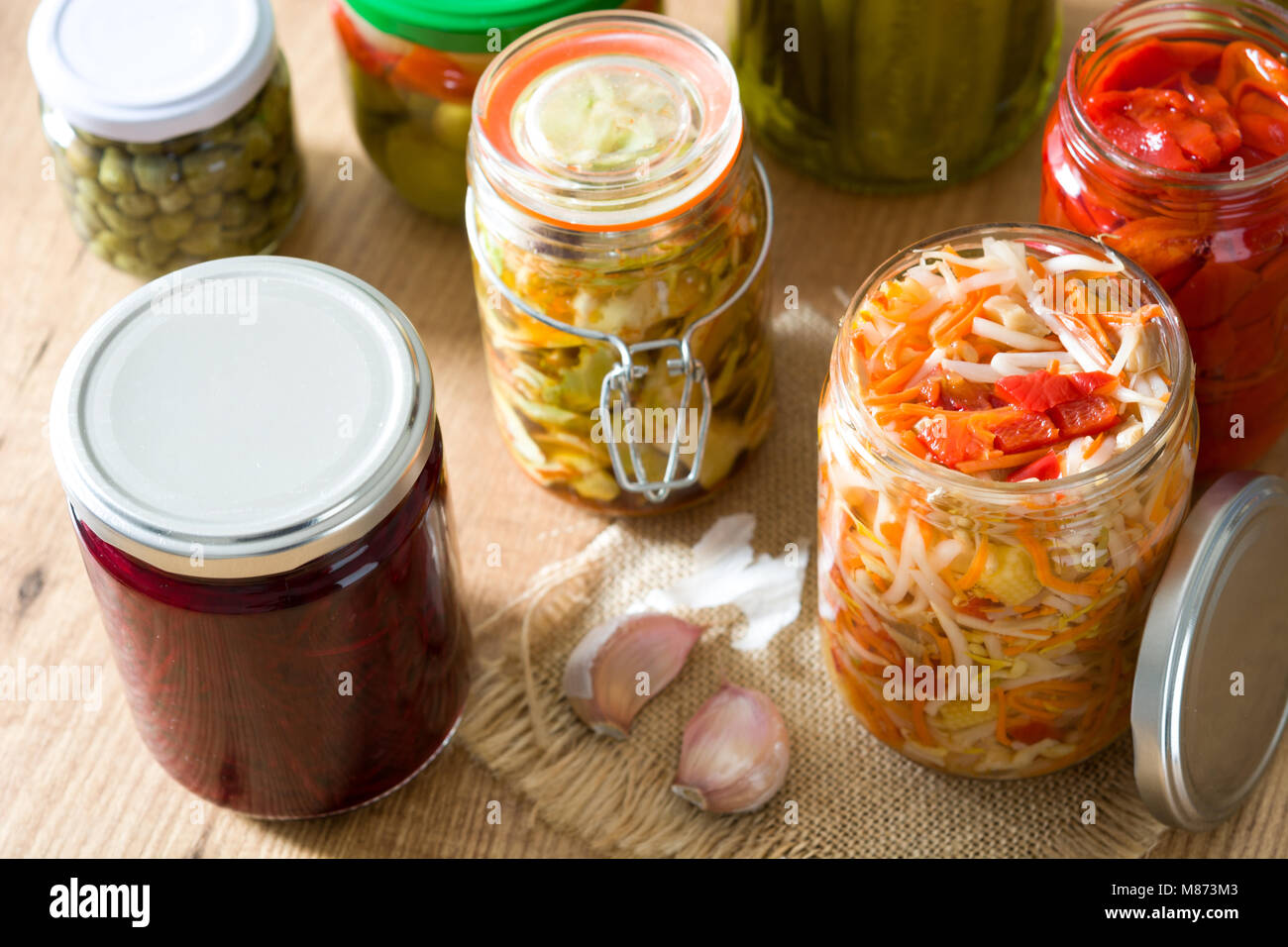 Fermented preserved vegetables in jar on wooden table. Stock Photo