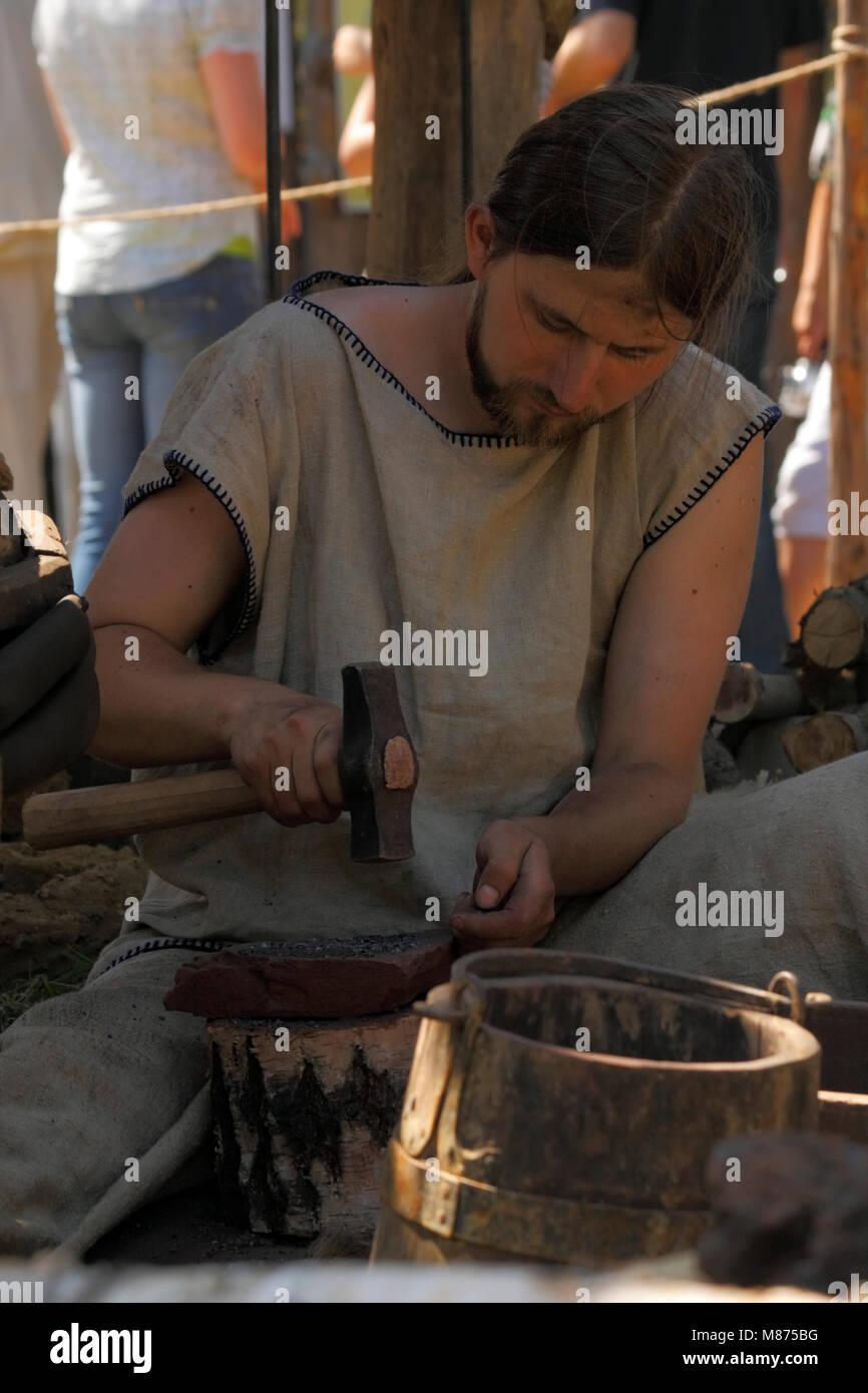 Man demonstrate crushing of iron ore for use in bloomery at Archeological Festival Dymarki Swietokrzyskie. Nowa Slupia, Poland, 21-22 August 2010. Stock Photo