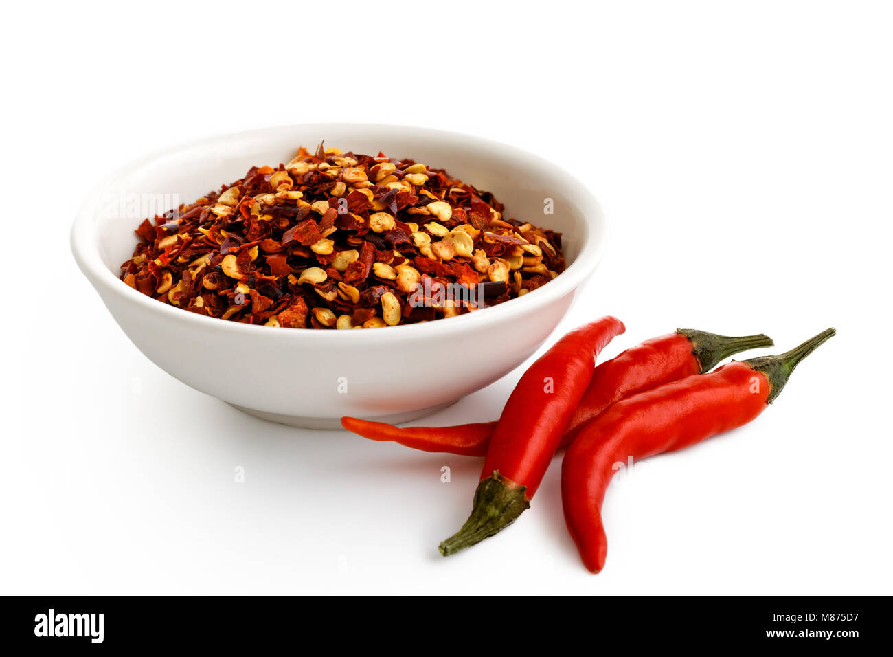 Coarsely ground chilli peppers in white ceramic bowl isolated on white. Fresh chillies Stock