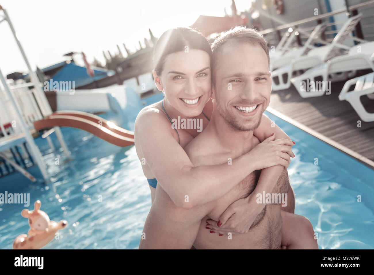 Excited young woman and man embracing in swimming pool Stock Photo - Alamy