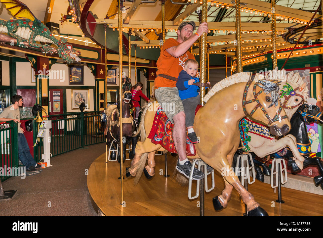 Parent and young son on carousel horse at Carousel for Missoula amusement park in Missoula, Montana, USA Stock Photo