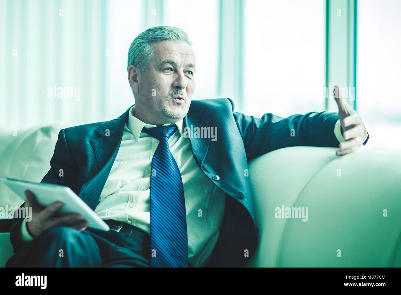 successful businessman with digital tablet sitting on the sofa in the private office Stock Photo