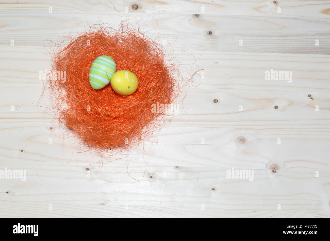 Color Easter eggs and straw on wood background bird nest Stock Photo