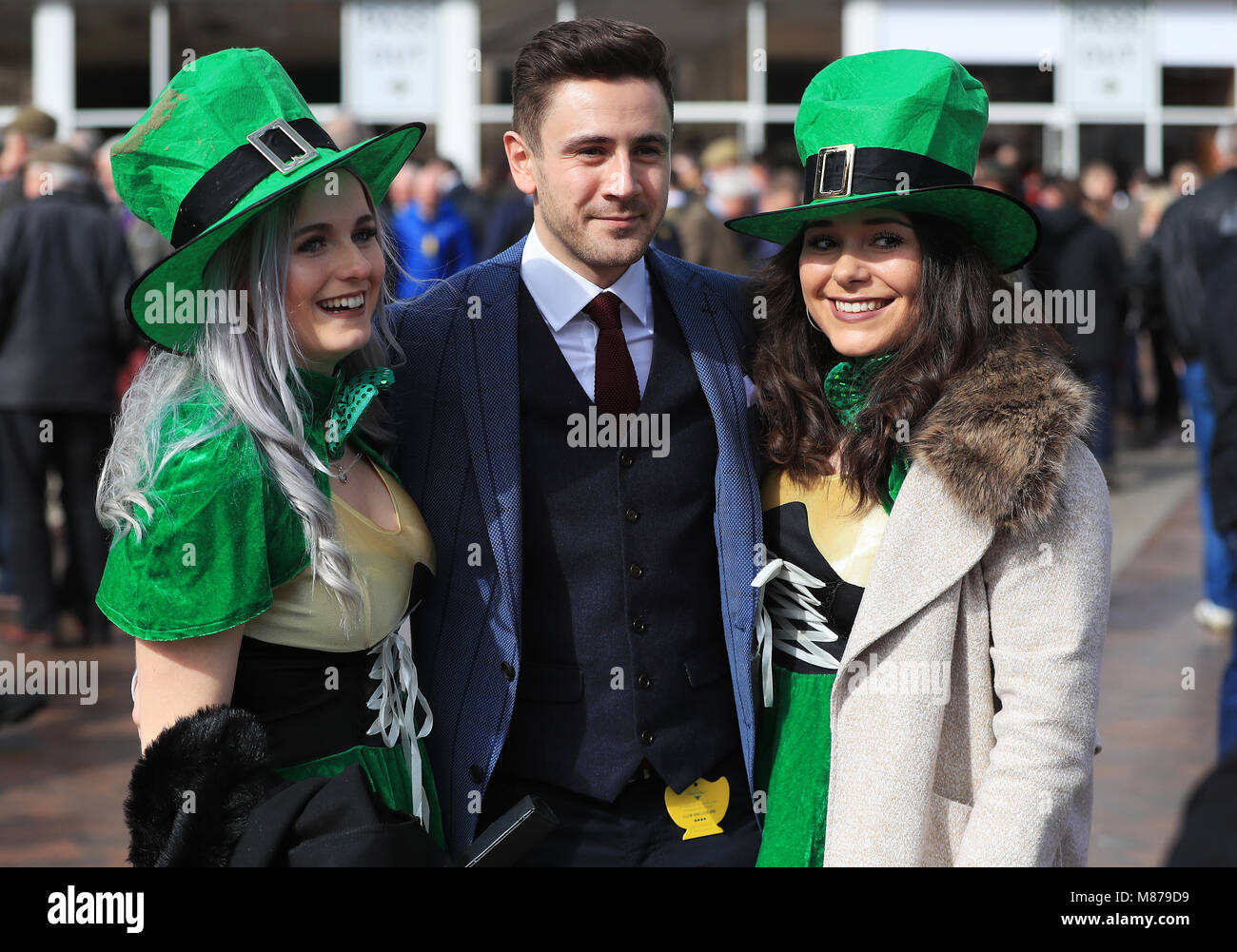 A racegoer poses for a photograph with two women dressed in Irish
