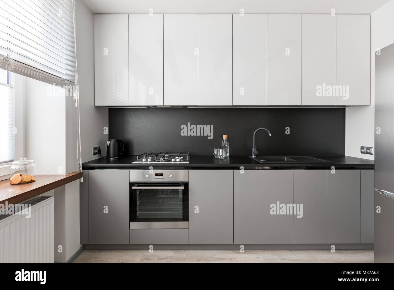 Modern, elegant interior with black worktop, gray and white kitchen unit Stock Photo