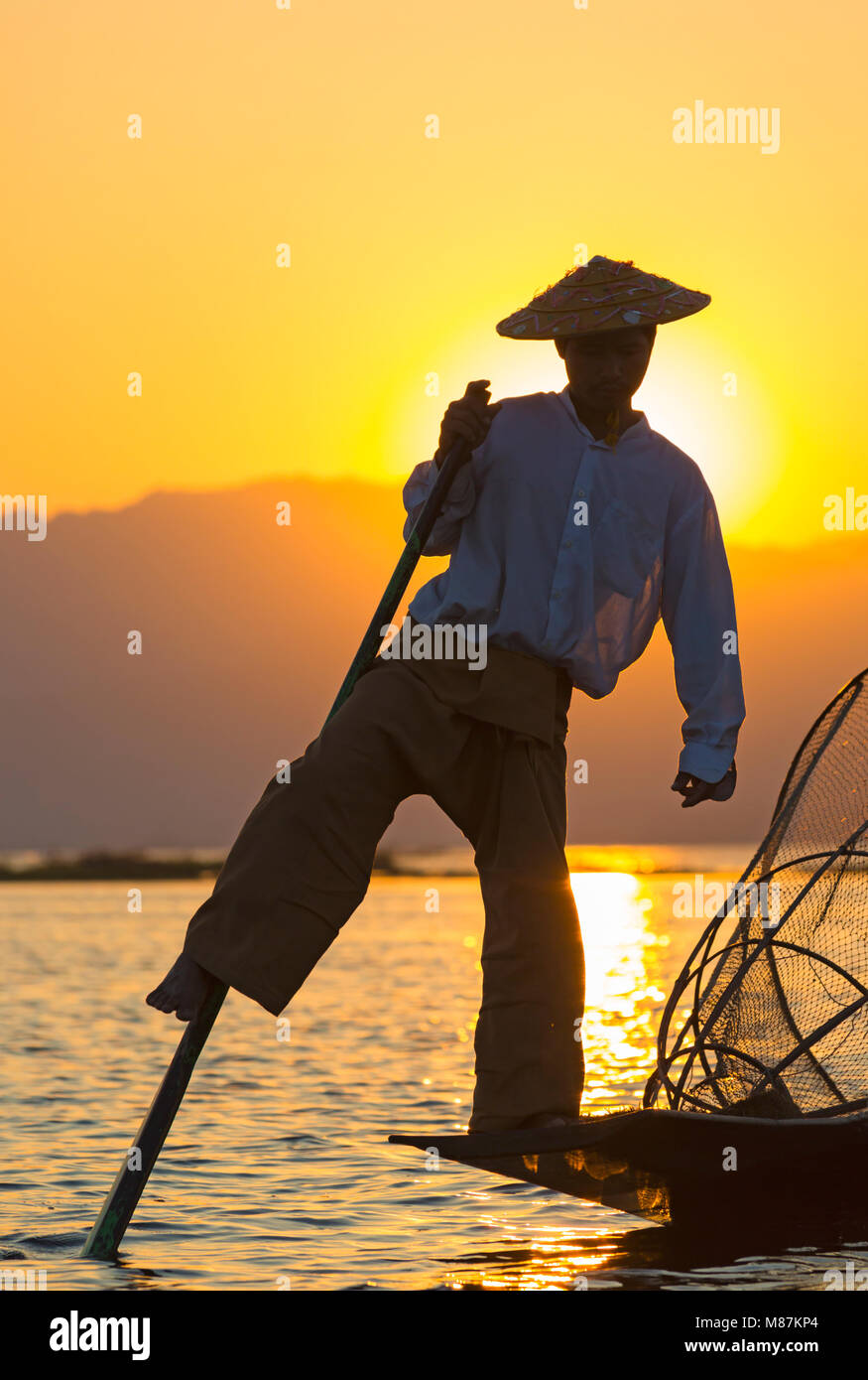 Intha leg rowing fishermen at sunset at Inle Lake,  Myanmar (Burma), Asia in February - fisherman standing on one leg Stock Photo