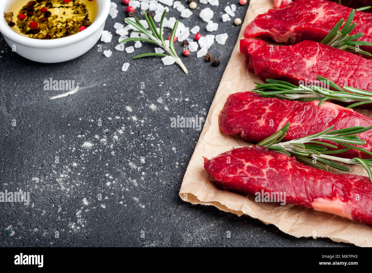 Raw meat on dark background. Raw beef stroganoff with herbs and spices