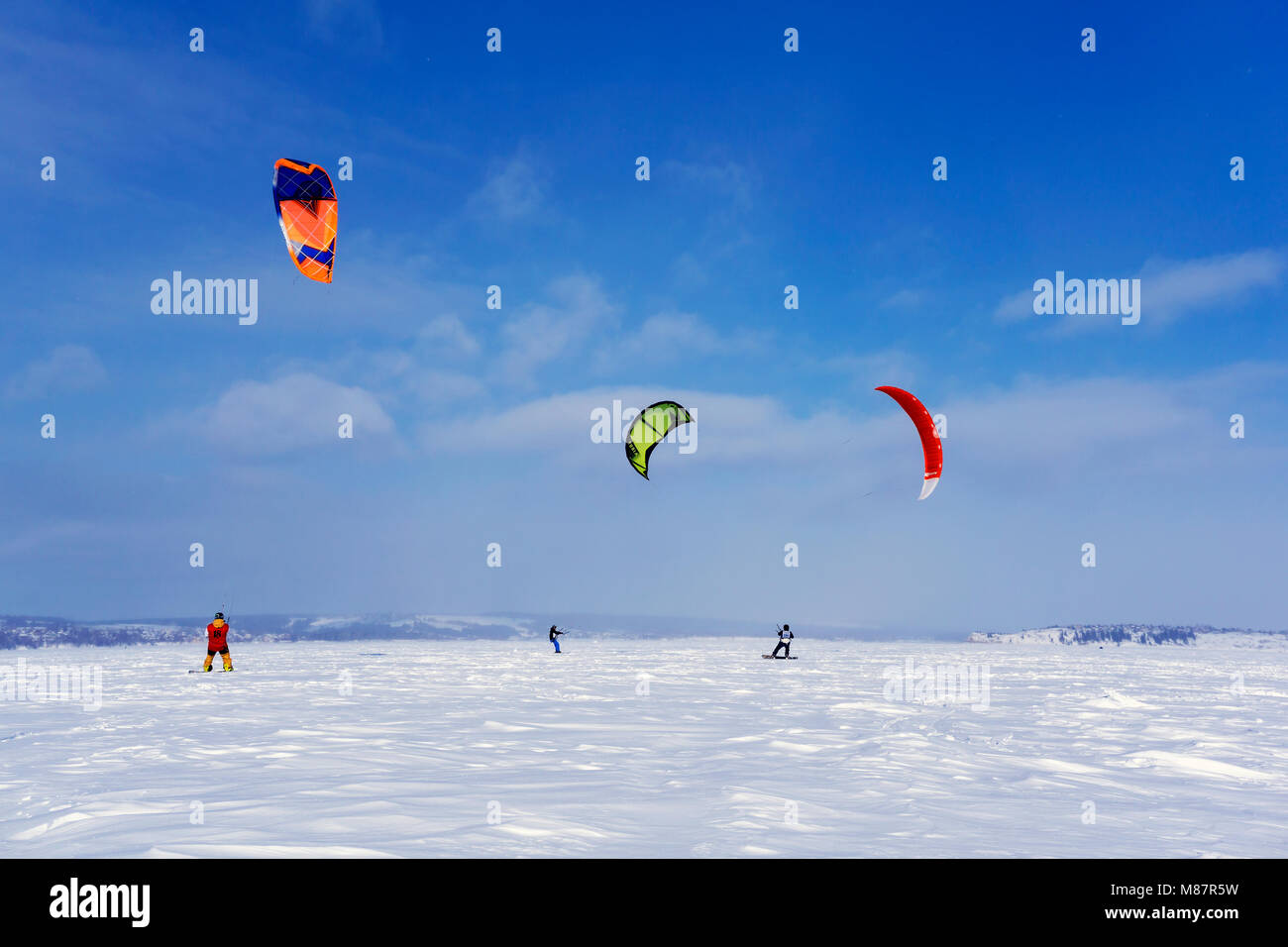 PERM, RUSSIA - MARCH 09, 2018: snow kiters train on the ice of a frozen lake in the background of a winter landscape Stock Photo
