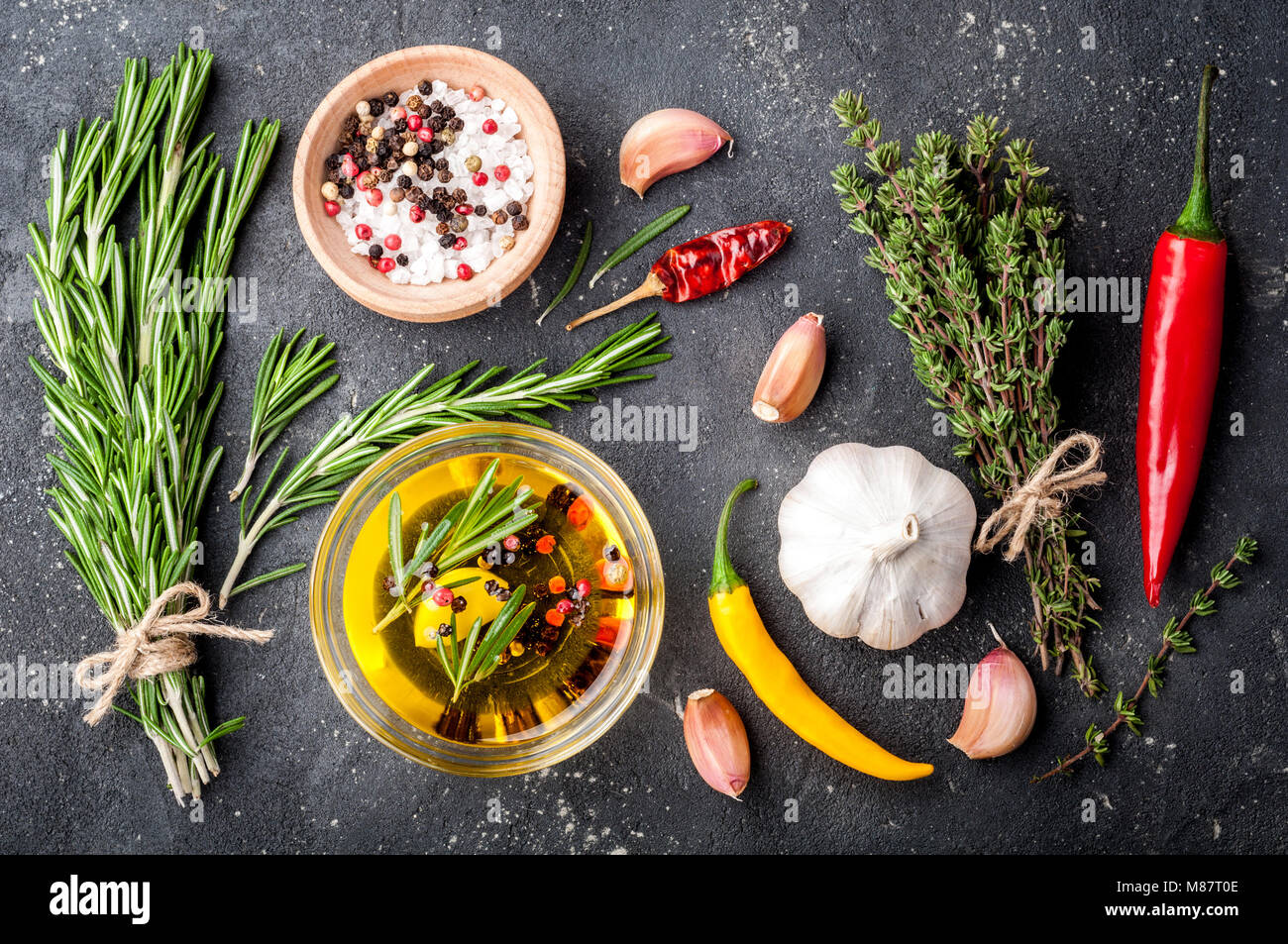 Herbs and spices. Rosemary, thyme, chili, garlic, olive oil, salt and pepper on dark table. Cooking ingredients. Top view Stock Photo