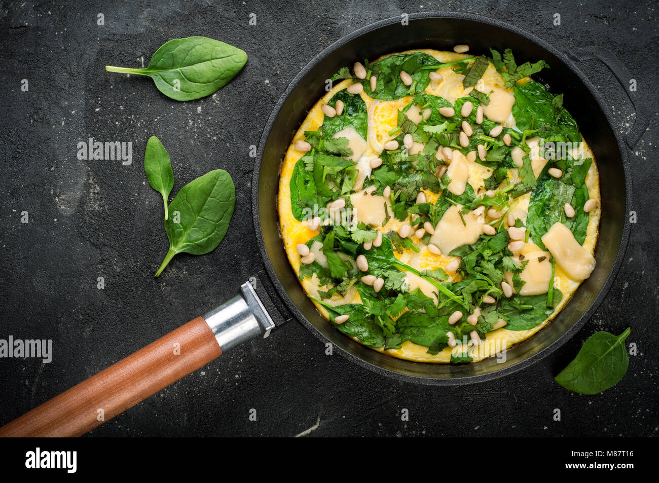 Omelet with eggs, spinach, pine nuts and vegetables. Spinach tortilla