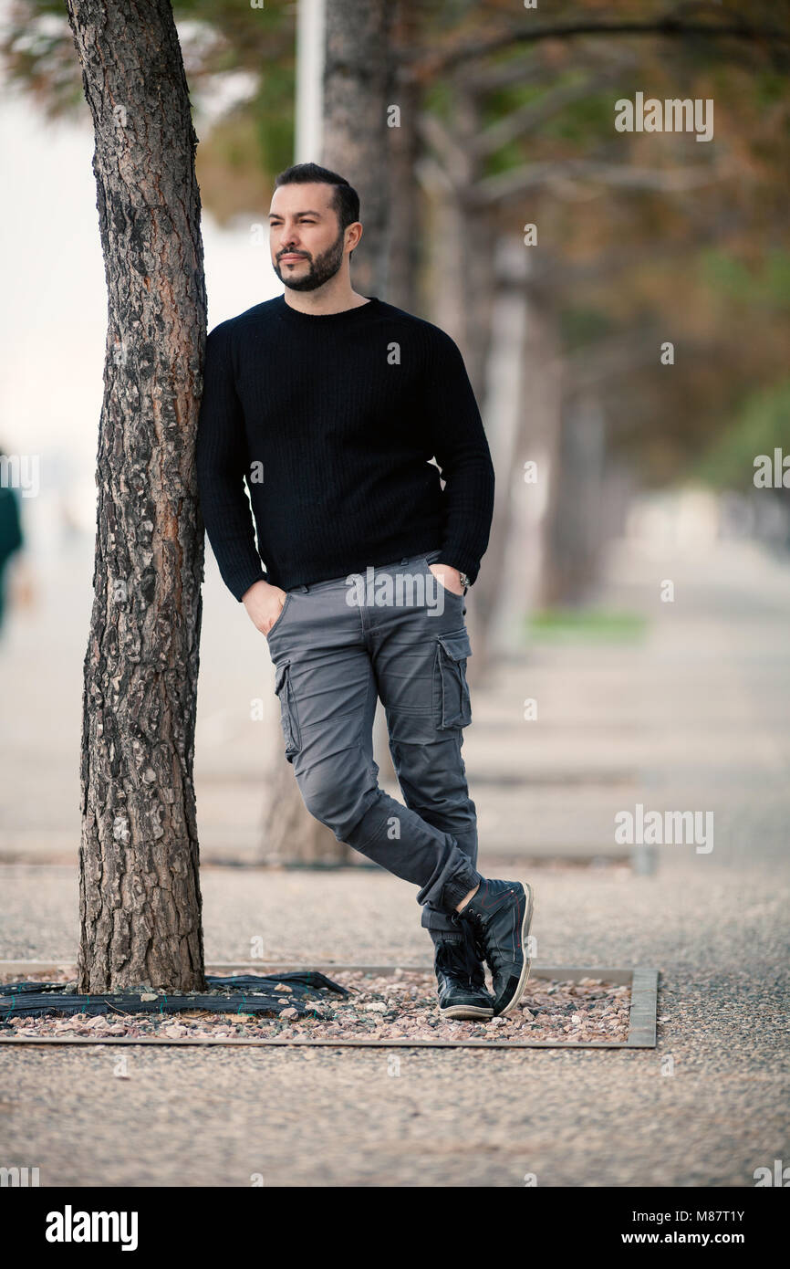 confident tough handsome man posing leaning against a tree shot with M87T1Y