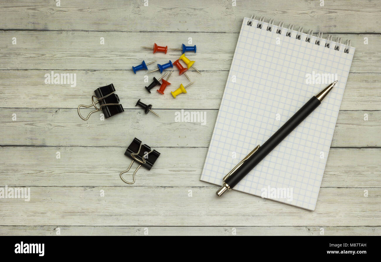 Stationery: blank notepad, pens, buttons, on a wooden gray desk. Top ...