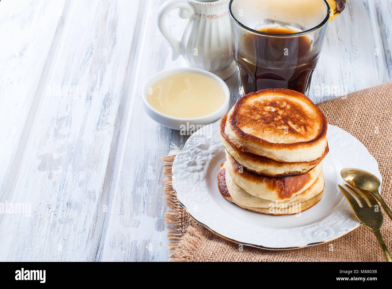 Stack of homemade pancakes no butter or syrup in a dish with coffee and