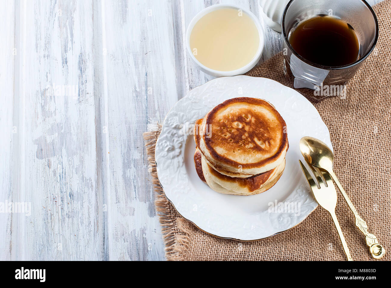 Stack of homemade pancakes no butter or syrup in a dish with coffee and