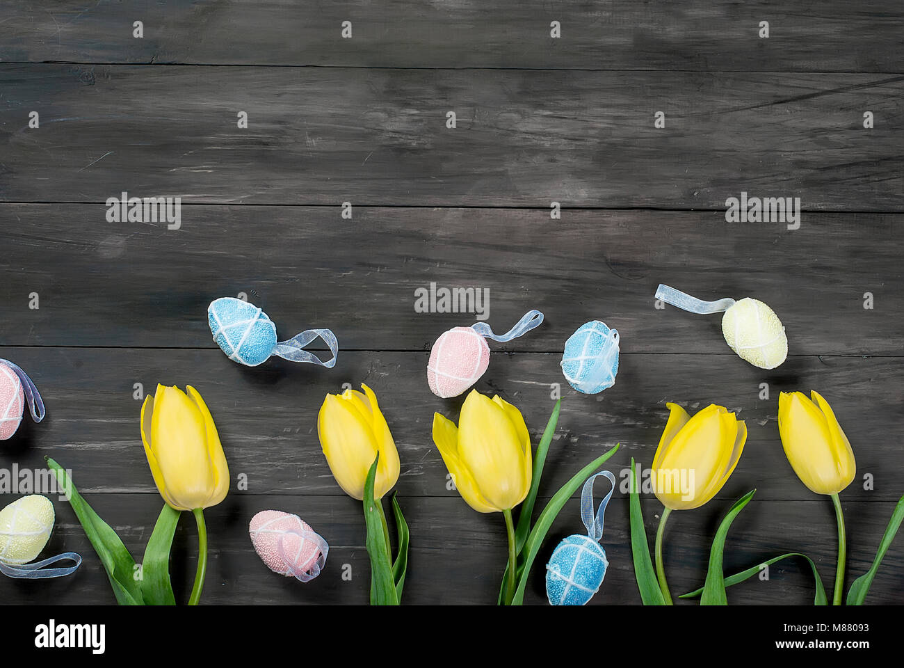 bouquet of yellow tulips and colored toys easter eggs on vintage dark ...