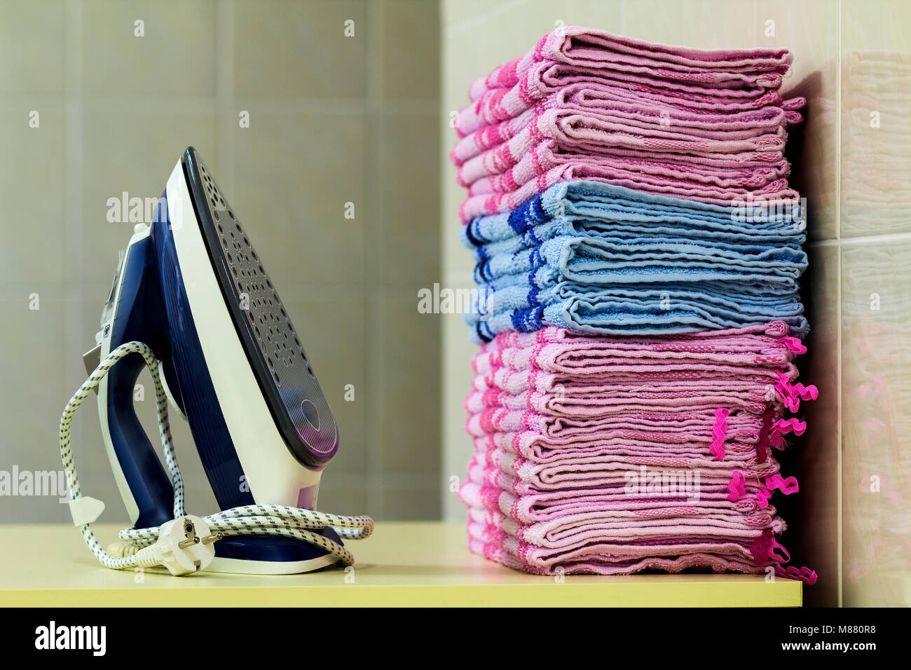 Ironing linen with steam generator. A stack of ironed towels lying next