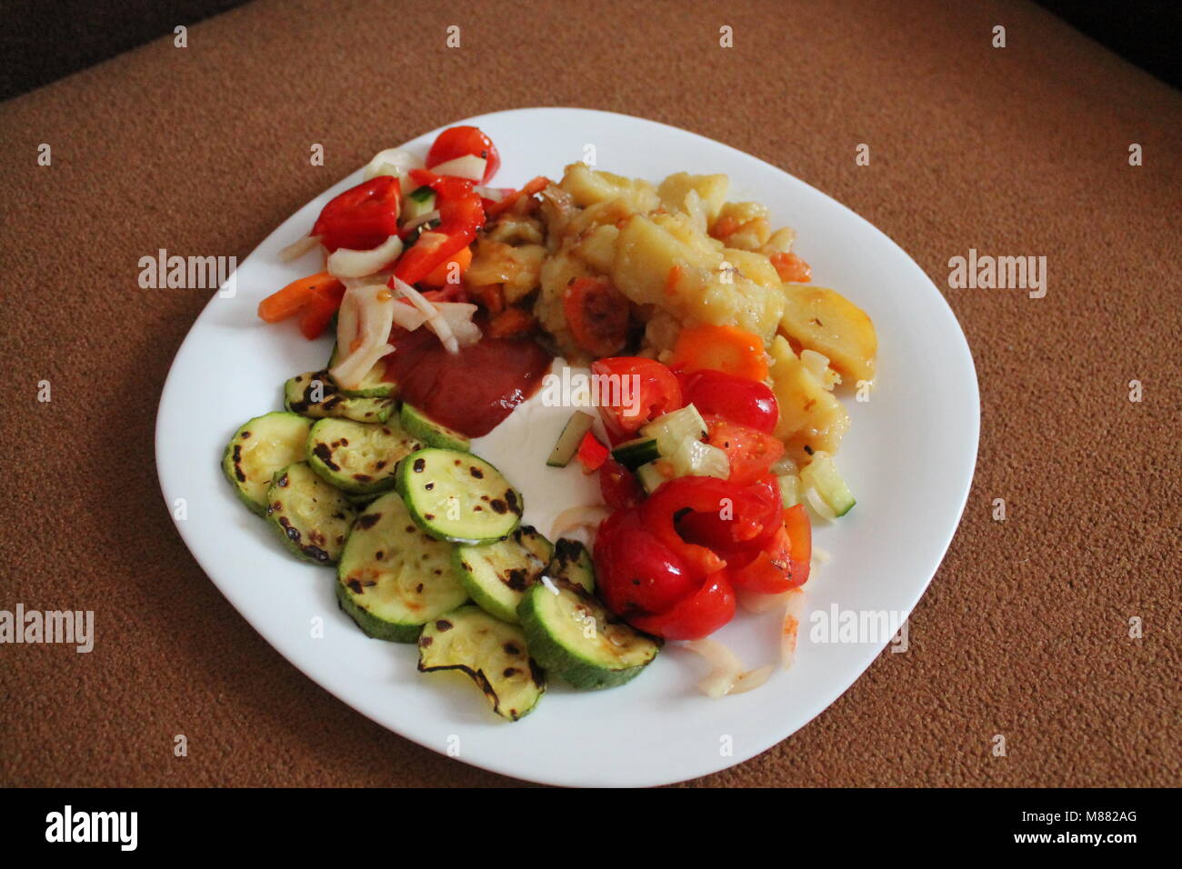 appetizing colorful vegetarian dinner fresh soft potato, juicy zucchini, salad from tomato and paprika under sweet sauce Stock Photo