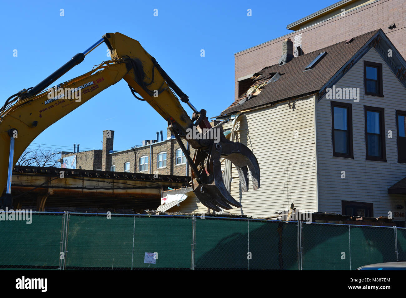 Chicago, Illinois, USA, 15 March 2018: Construction crews for the City of Chicago tear down a home north of the Belmont CTA Station. The city is demolishing 14 buildings at a cost of $320 million to make way for the Brown Line Flyover. The Flyover is controversial with residents of the Lakeview neighborhood who feel it is destroying the neighborhood and creating permanent scars. Once completed in 2024 the flyover is expected to reduce commute times by 4:00 and add capacity to the Red, Purple and Brown Lines. Credit: D Guest Smith/Alamy Live News Stock Photo
