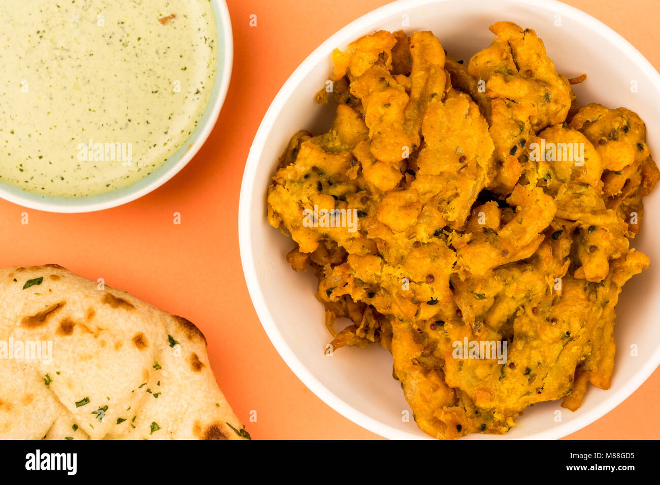 Indian Style Snack Of Fried Onion Bhajis Against An Orange Background