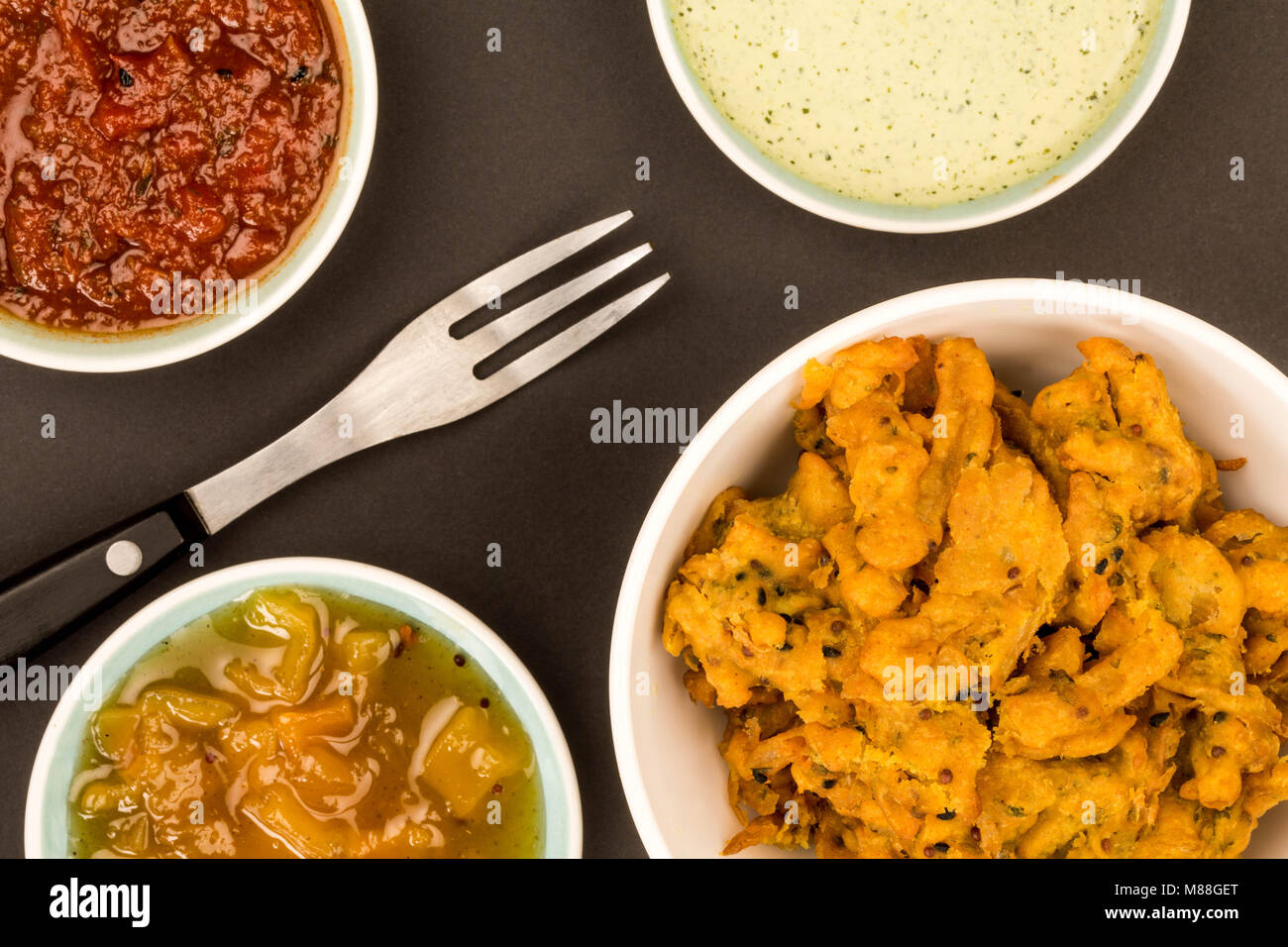 Indian Style Snack Of Fried Onion Bhajis Against A Black Background