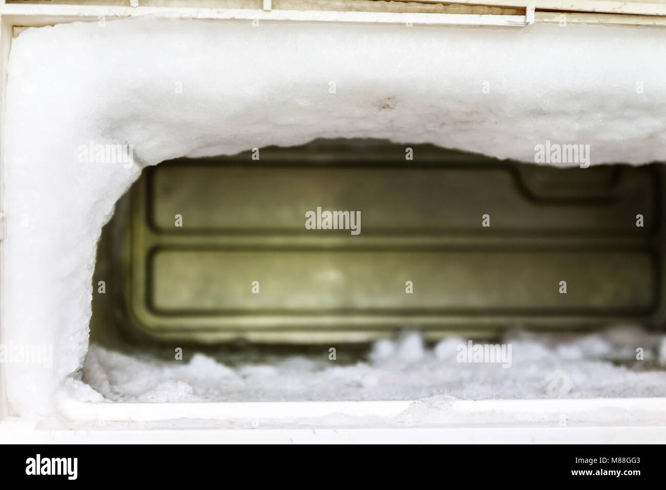 The freezer of a refrigerator is full of huge amounts of ice due to has no automatic defrost function. The fridge is a very old model that the user ha Stock Photo